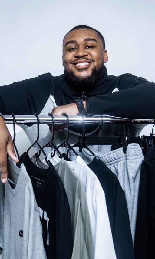 Devin leaning on a rack of Nike apparel